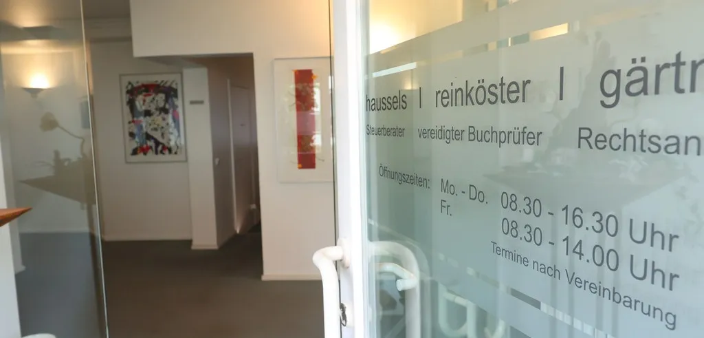 Die Glastür zur Kanzlei mit dem Schriftzug haussels reinköster gärtner und den Öffnungszeiten.