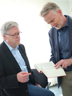 Die beiden Partner sehen gemeinsam in ein aufgeschlagenes Buch.